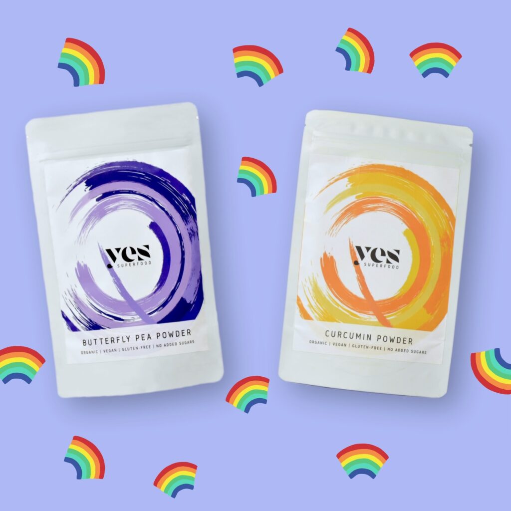 Yes Superfood Curcumin és Butterfly Pea porok pasztell háttéren, szivárvány ikonokkal díszítve.